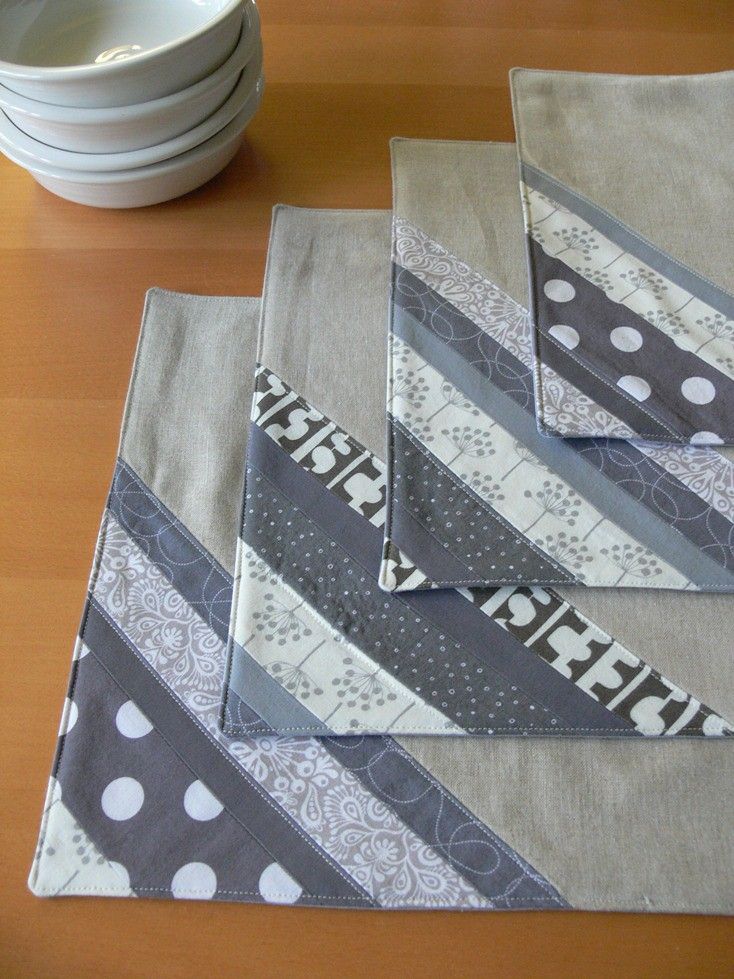 three pieces of fabric sitting on top of a wooden table next to plates and bowls