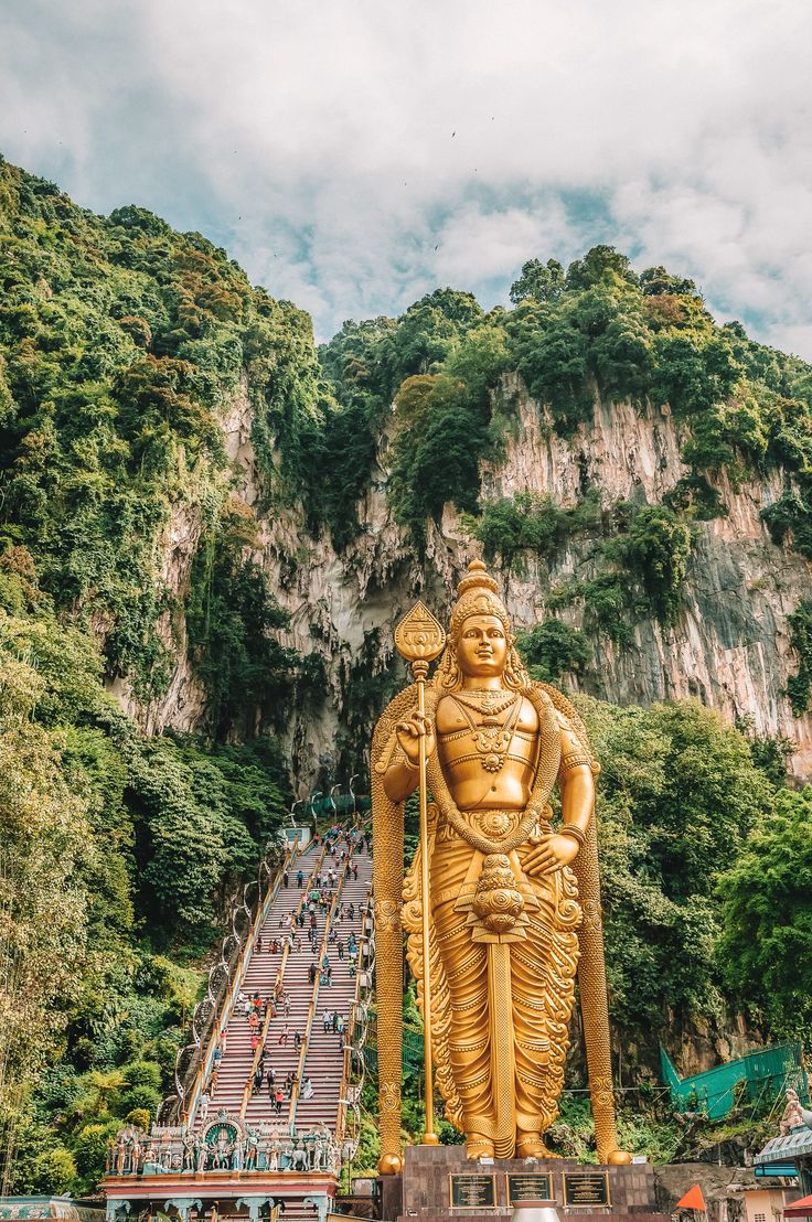 there is a large golden statue in the middle of a mountain side area with stairs leading up to it