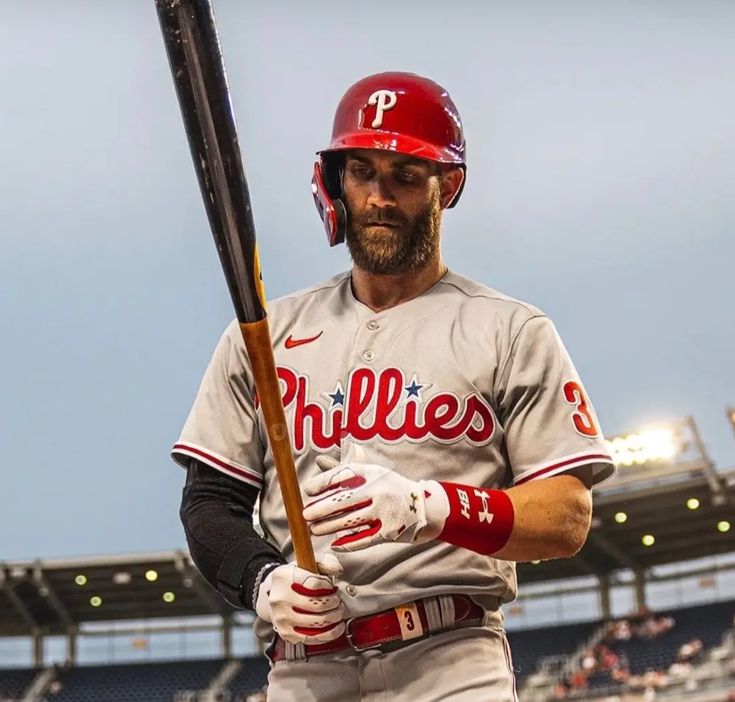 a baseball player holding a bat in front of an empty bleachers at night