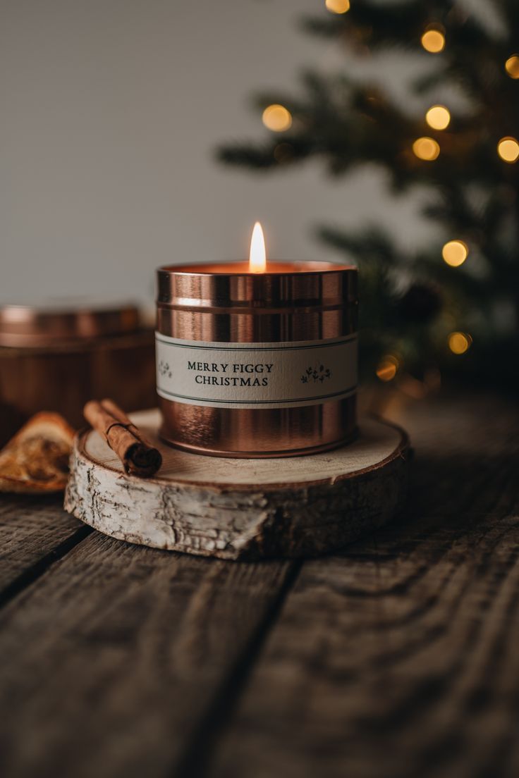 a candle sitting on top of a wooden table next to some cinnamons and a christmas tree