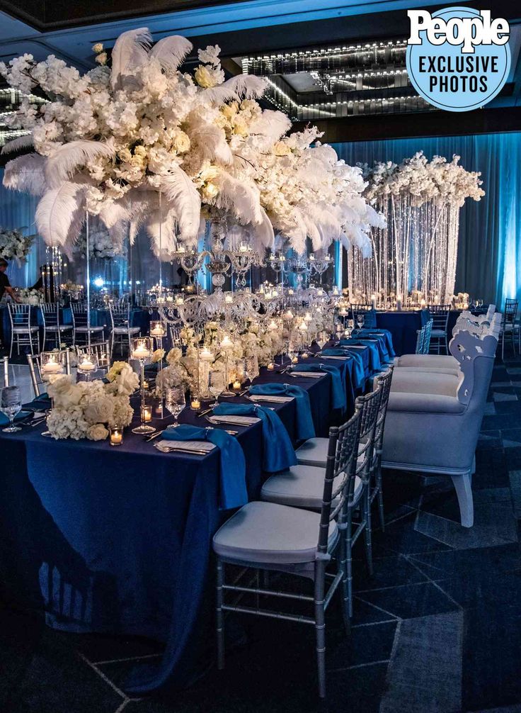 a table set up with blue linens and tall centerpieces for an event