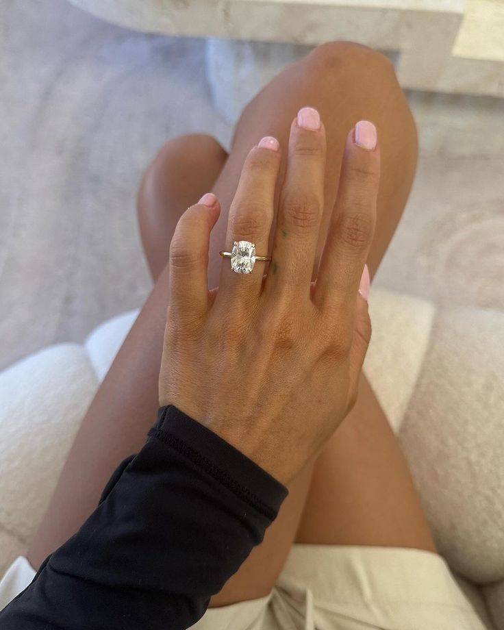 a woman's hand with a diamond ring on her left wrist, sitting on a bed