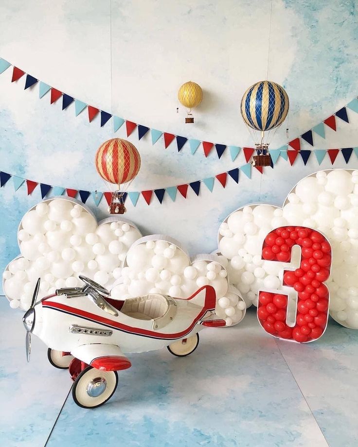 an airplane with balloons attached to it in front of a number three balloon wall decoration