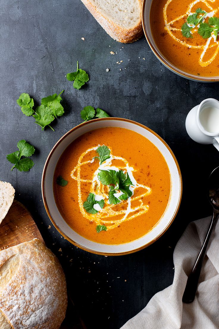 two bowls of soup with bread on the side