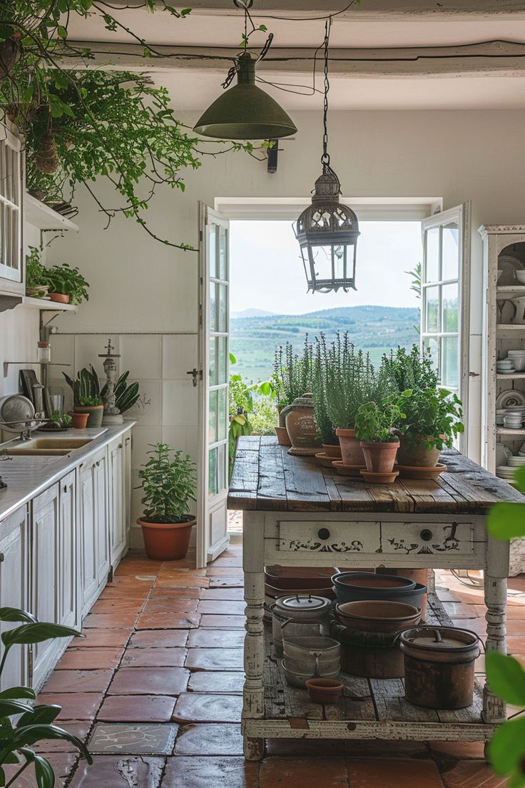 an open kitchen with potted plants on the island and hanging lights over the sink