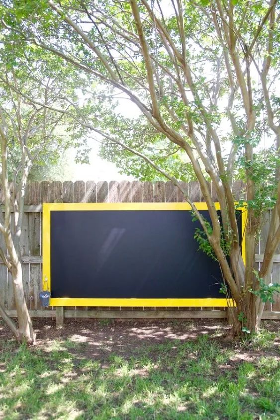 a black and yellow sign sitting in the middle of a yard next to some trees