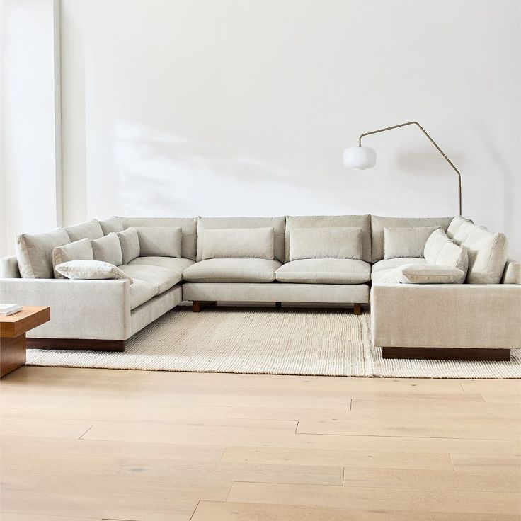 a living room with a large sectional couch and coffee table in front of the wall