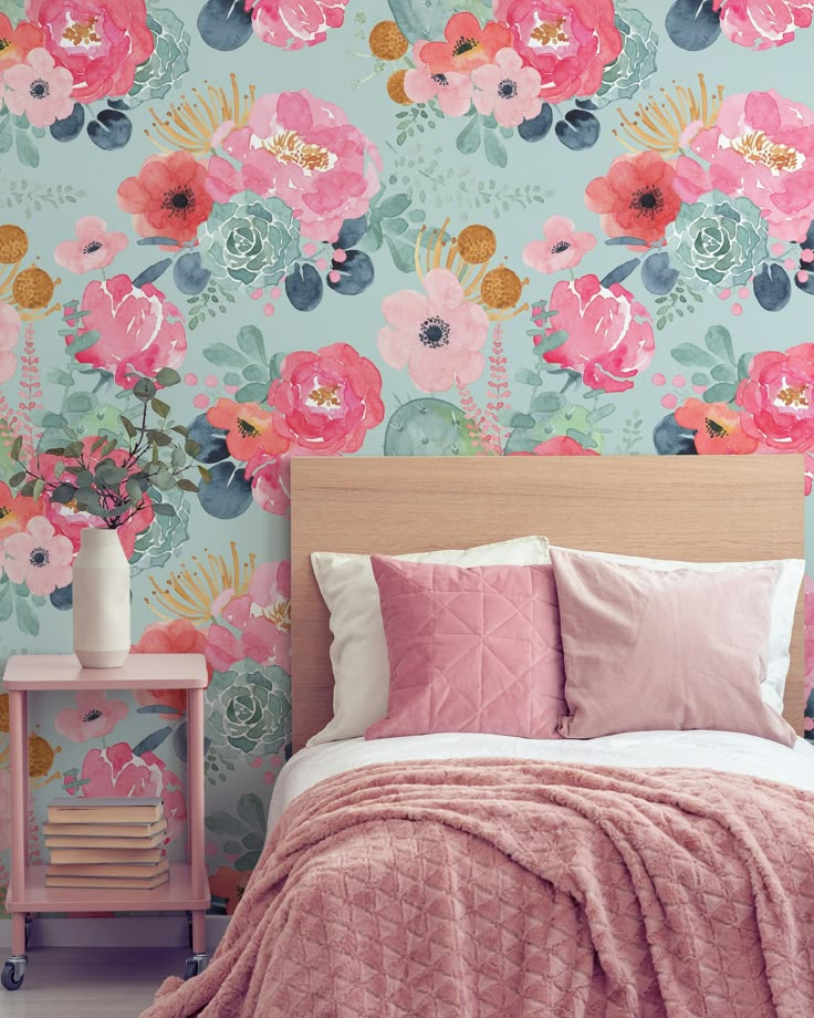 a bed with pink and blue floral wallpaper next to a wooden headboard in a bedroom