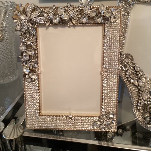 an ornate photo frame sitting on top of a table next to glass vases and other items