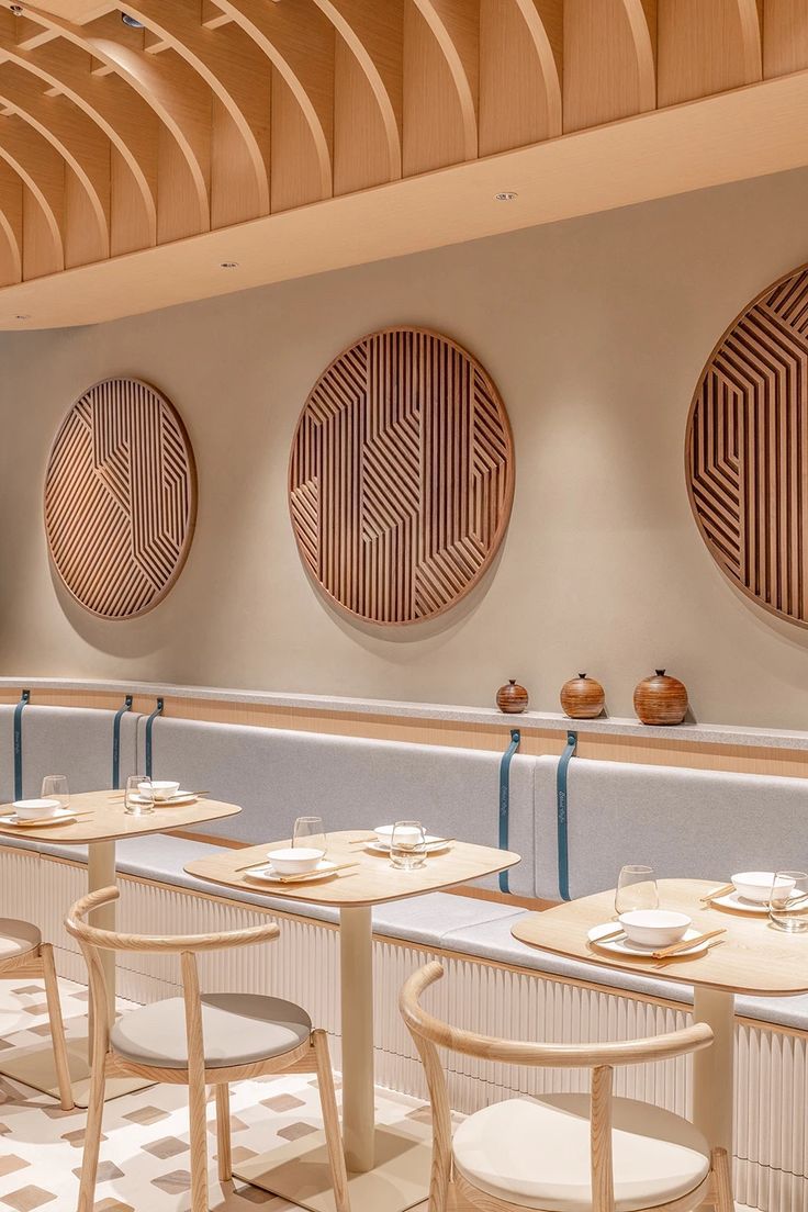 an empty restaurant with round wooden tables and white chairs in front of the counter area