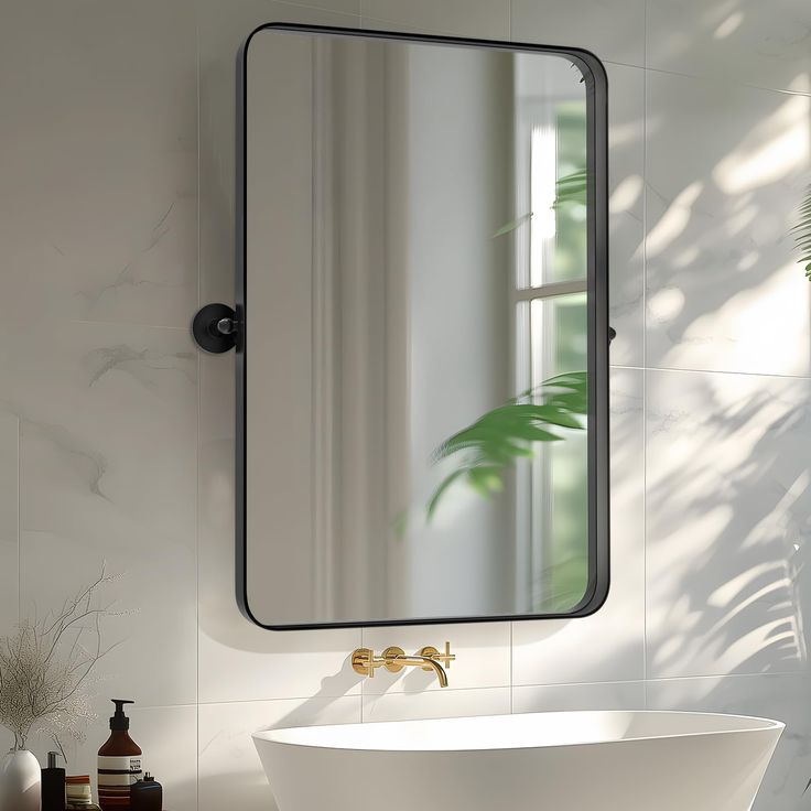 a white bath tub sitting under a bathroom mirror next to a sink and potted plant