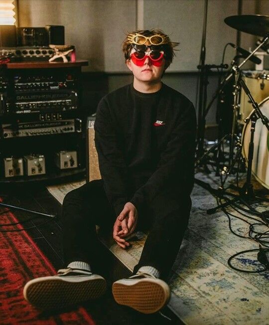 a young man sitting on the floor in front of some music equipment