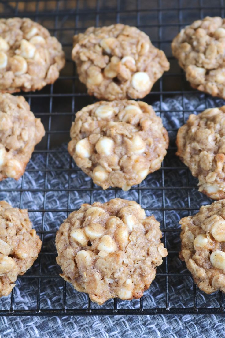 several cookies cooling on a wire rack with white chocolate chips in the middle and oatmeal toppings