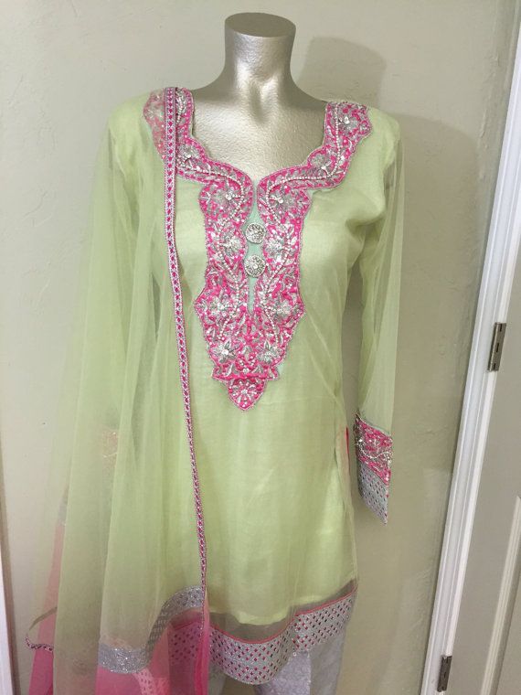 Dress Description: Light green net kurta style shirt with pink and gold zari neckline. Sleeves are bell bottom with 2 kinds of pink/gold combination laces. Dupatta also has trims on borders. Pants are silver plain jamawar fabric. Size: Custom and standard sizing avaiable Delivery: Green Punjabi Suit, Gotta Work, Pakistani Suit, Kurta Style, Mother Daughter Dress, Indian Suits, Pakistani Suits, Bell Bottom, Style Shirt