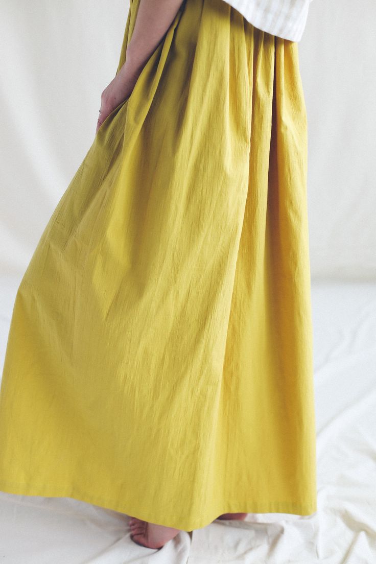 "Flowy crinkle cotton skirt. - Handmade in our studio from crinkle cotton - Hand ruffled A-line silhouette - Elasticated waist with a drawstring - Ankle length - Side seam pockets FABRIC&CARE 97% cotton 3% spandex. Available in the following colors: - chartreuse yellow - charcoal grey* (not available at the moment) - raspberry pink* (sold out) - mint Hand wash or gently machine washable 30oC, hang dry recommended, iron on medium. Do not tumble dry, do not bleach. SIZE&FIT Simona is weari Cotton Maxi Skirt With Relaxed Fit And Gathered Detail, Casual Cotton Maxi Skirt With Gathered Waist, Cotton Flowy Lined Skirt Bottoms, Flowy Cotton Lined Skirt Bottoms, Relaxed Fit Gathered Cotton Skirt, Cotton Bottoms With Gathered Waist And Flowy Skirt, Cotton Bottoms With Gathered Waist And Flowy Fit, Cotton Lined Maxi Skirt, Solid Cotton Lined Maxi Skirt