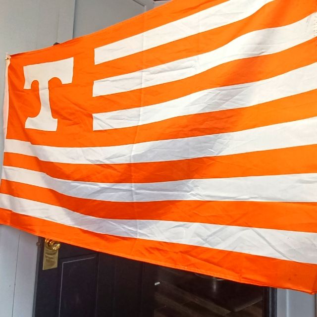 an orange and white flag hanging from the side of a building in front of a doorway