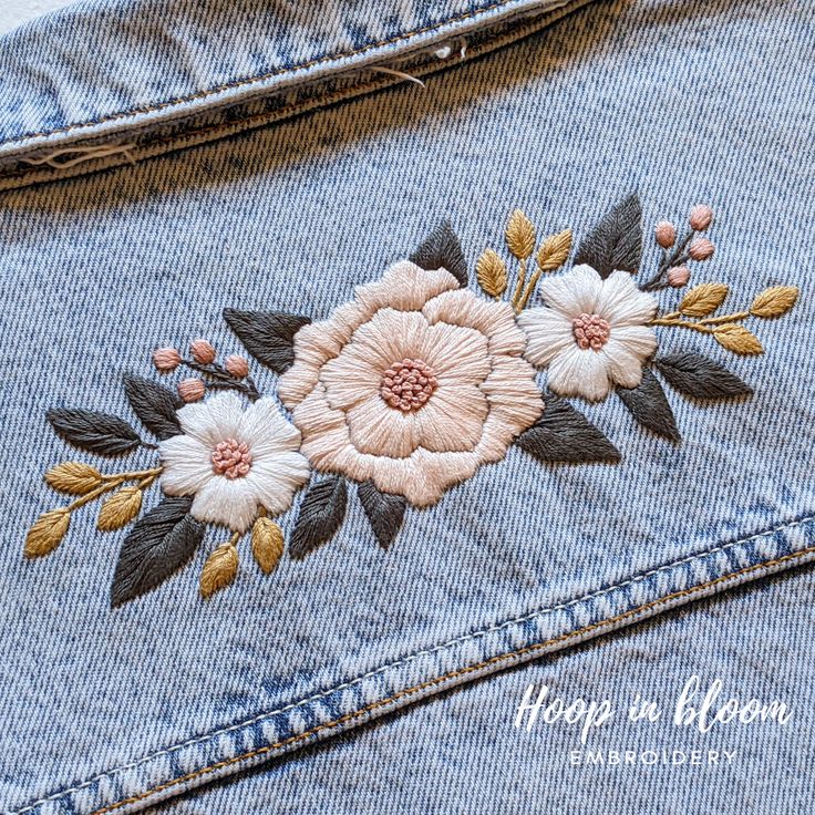 embroidered flowers on the back of a jean jacket with text overlay that reads happy in bloom