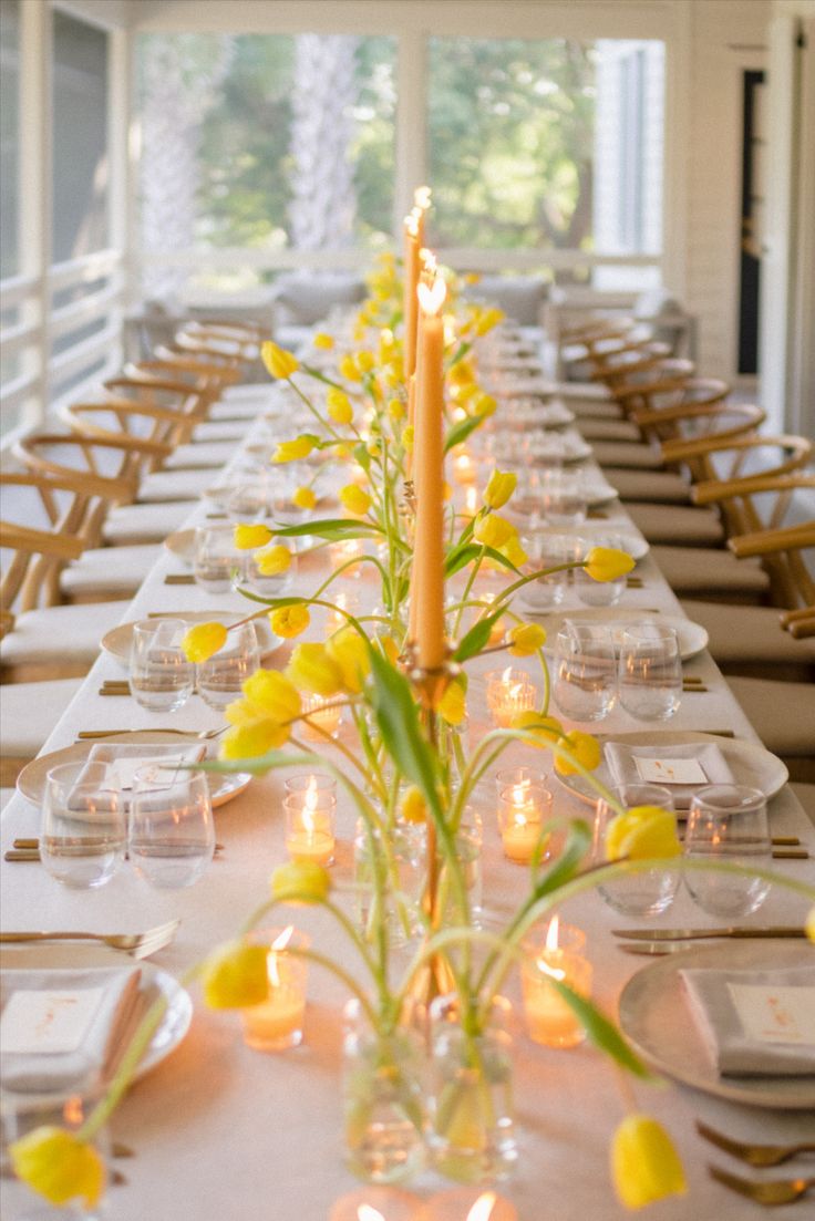 a long table with yellow flowers and candles