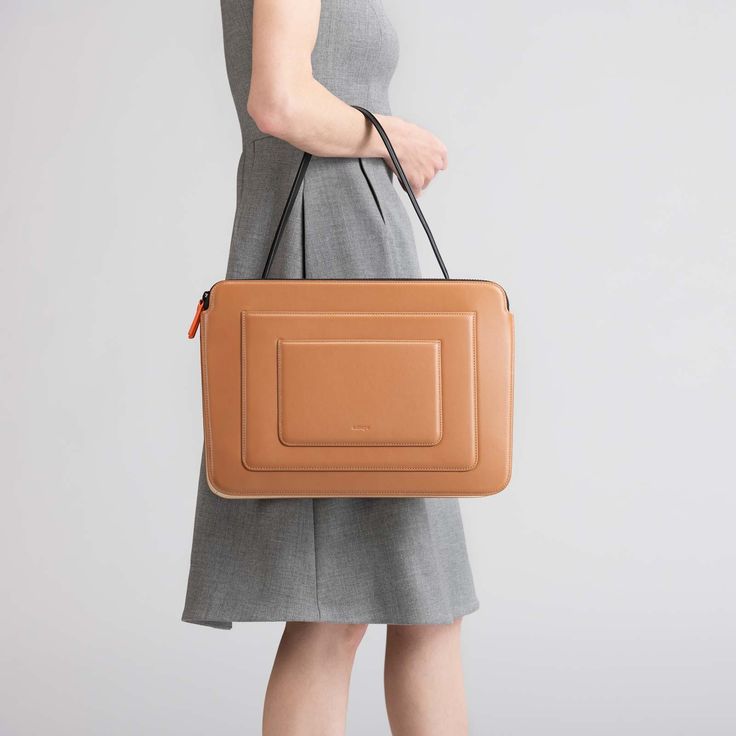 Designed in a silhouette inspired by Art-Deco style, this bag is expertly crafted from Italian calf leather with microsuede lining. Packs a ton of features in a slim, compact space so you can carry your office life in the bag — including a 16” Macbook Pro. It has additional two tight slots on the front that you can fit your notebook, phone or tablet. Crafted from Italian cow leather. Soft coating zippers ensure your laptop won't get scratched. h:28 X w:39.5 X d:7 cm (11 X 15.5 X 2.75 in) Handle Modern Rectangular Laptop Bag With Detachable Handle, Modern Shoulder Laptop Bag With Detachable Handle, Modern Laptop Shoulder Bag With Detachable Handle, Modern Briefcase With Detachable Handle, Modern Brown Shoulder Bag With Top Carry Handle, Modern Cognac Satchel For Office, Modern Laptop Bag With Top Handle, Modern Cognac Briefcase With Top Handle, Modern Top Handle Briefcase