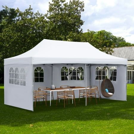 a large white tent set up in the grass with tables and chairs under it on a sunny day