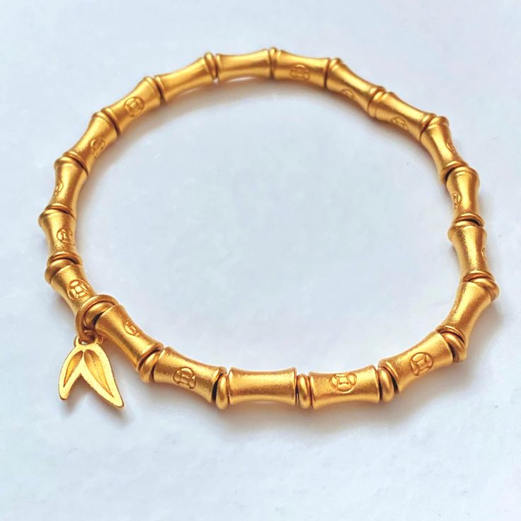 Bamboo Bracelet Gold 24K Plated Lucky Wealth Prosperity 🎋 Bracelet Approx. size: 6.5 🎋 Stretch Elastic Bracelet  🎋 Bamboo 24K Gold Plated Beads (7mm x 4mm) Each bead has a money coin symbol. 🎋 24K Gold Plated Spacer Beads and Bamboo Leaf Charm  📷 Check out our instagram @little.rainbow.factory for more pictures/videos of this item Photos were taken in natural sunlight. Please keep in mind that colors may vary from the photos taken due to the settings on your phone or monitor display and surface. *Please note that jewelry may tarnish due to oxidization* Adjustable Symbolic Gold Beaded Bracelets, Gold Spiritual Charm Bracelet For Good Luck, Symbolic Gold Bangle Bracelet, Gold Hand-strung Name Bracelet Gift, Symbolic Gold Beaded Bracelets As Gift, Symbolic Gold Beaded Bracelets For Gifts, Gold Bangle Stretch Bracelet, Flexible Yellow Gold Stretch Bracelet Gift, Flexible Yellow Gold Stretch Bracelet For Gift