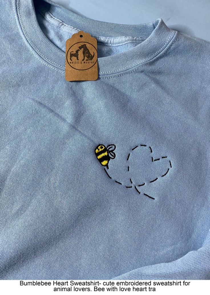 a blue t - shirt with a bee embroidered on the chest and a brown sticker attached to it