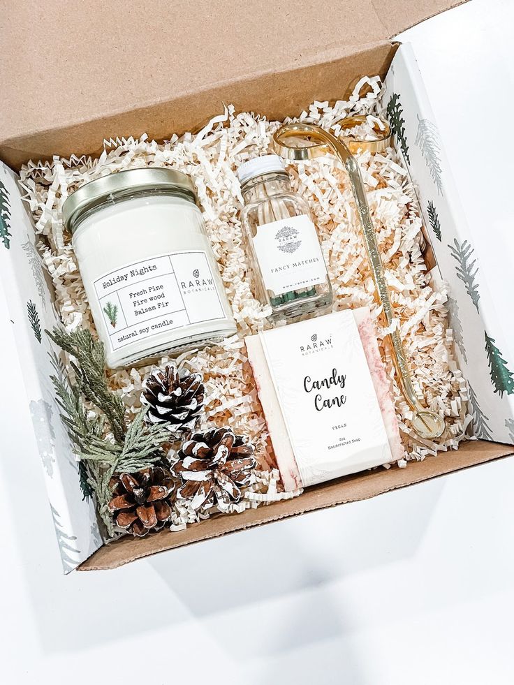 an open gift box containing candles, soaps and pine cones