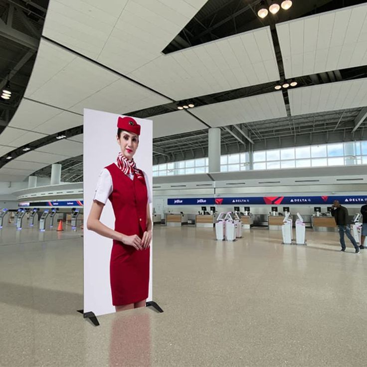 a woman in an airplane attendant's uniform is standing next to a large sign