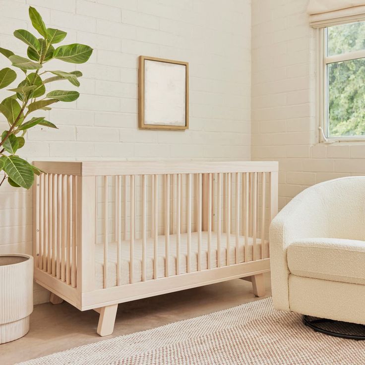 a white crib next to a potted plant in a room