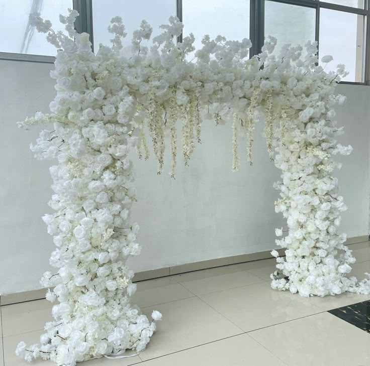 two white flowers are on the floor next to each other in front of a window