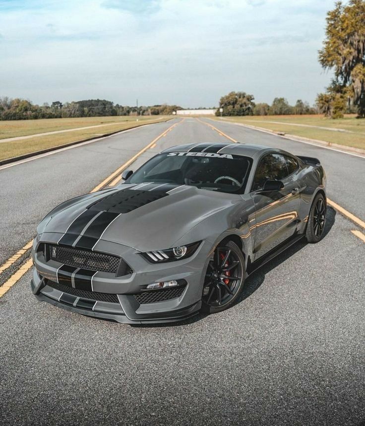 a gray mustang parked on the side of an empty road