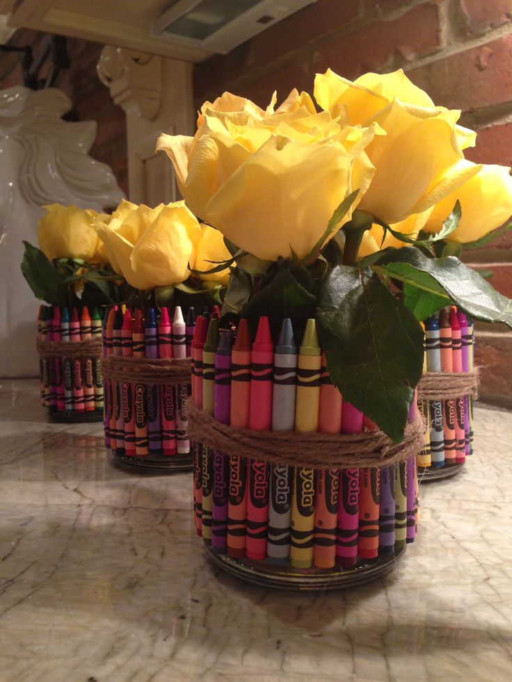 some crayons and yellow roses are in baskets