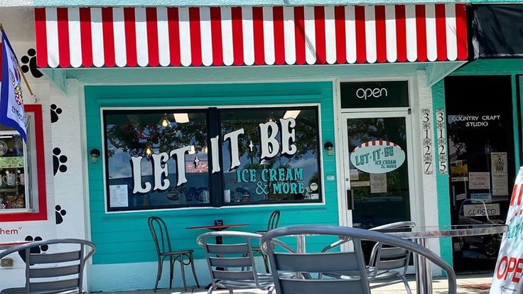 the outside of a small ice cream shop with tables and chairs in front of it