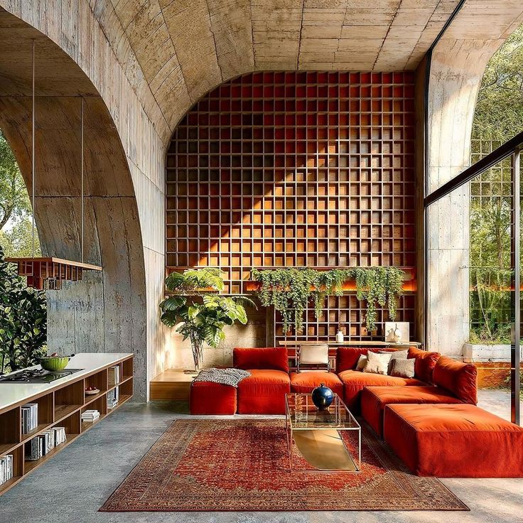 a living room with red couches and wooden shelves on the wall, surrounded by greenery