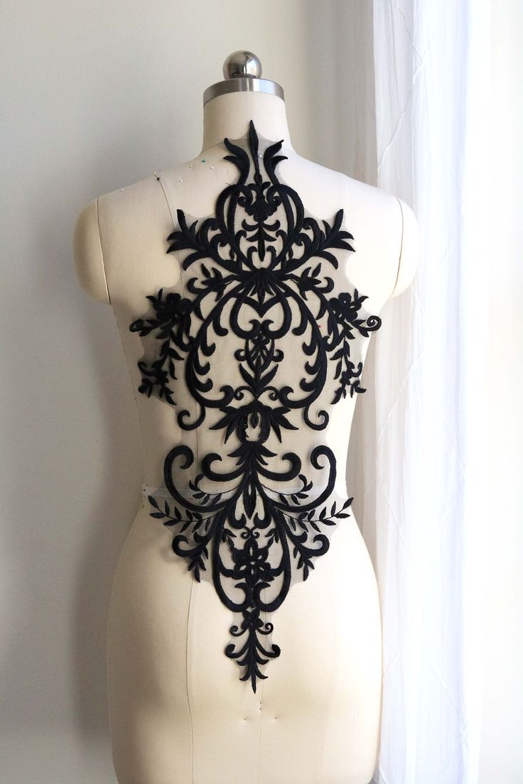 a white mannequin with an intricate black design on it's chest and back