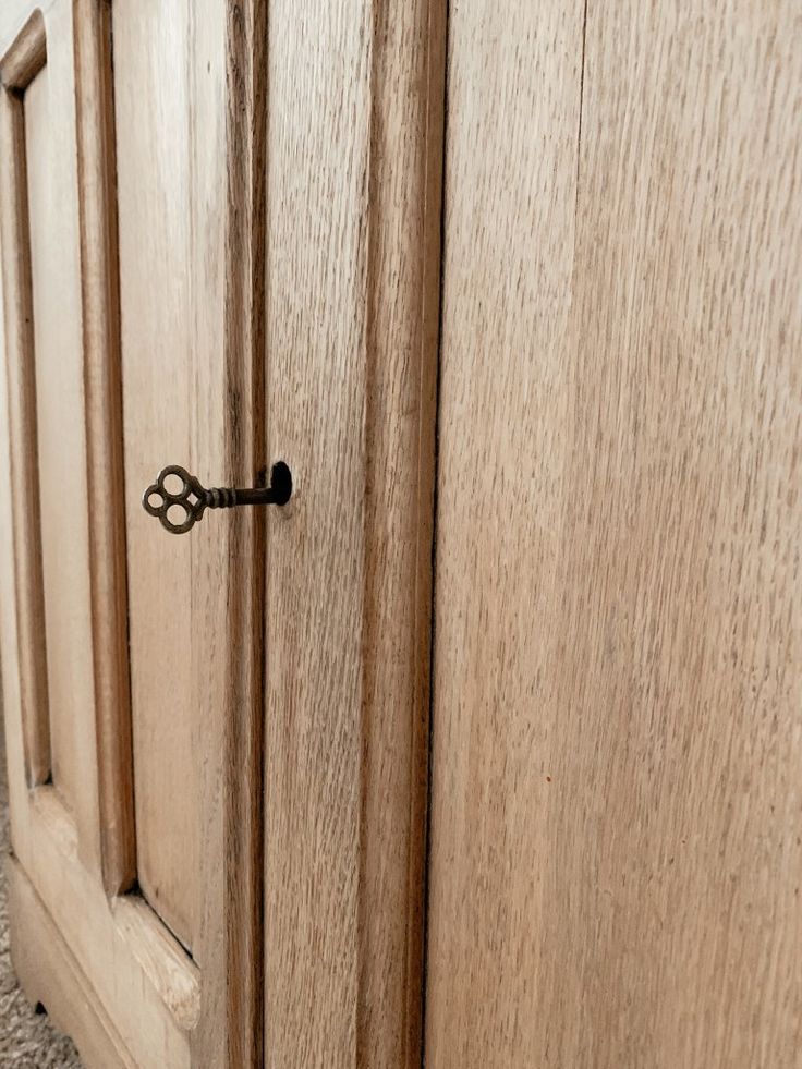 an open door with a key in it on the side of a wooden cabinet next to a carpeted floor