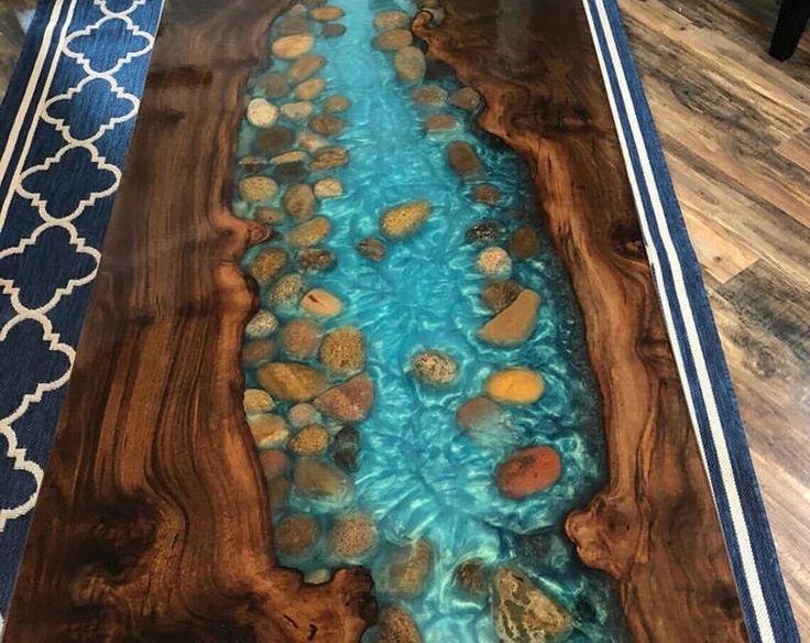 a wooden table with blue water and rocks in the middle on it's side