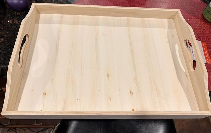 a wooden tray sitting on top of a black chair next to a red table cloth