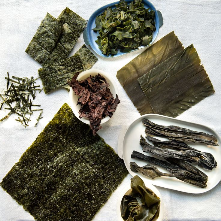 various foods are arranged on a white tablecloth with blue and white striped napkins