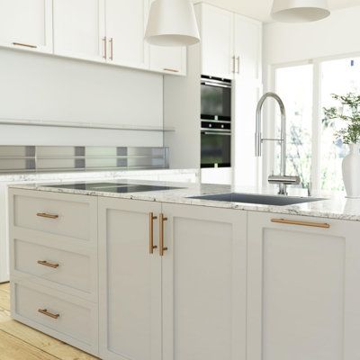 a large kitchen with white cabinets and marble counter tops, an island style sink and two hanging lights