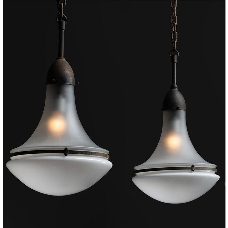 two pendant lights hanging from chains on a black background, one is white and the other is brown