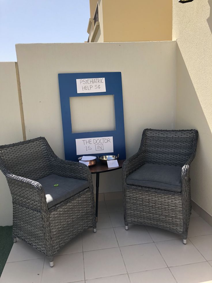 two wicker chairs sitting next to each other in front of a blue and white frame