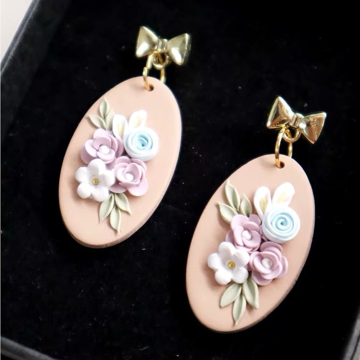 two pink earrings with flowers and bows on them