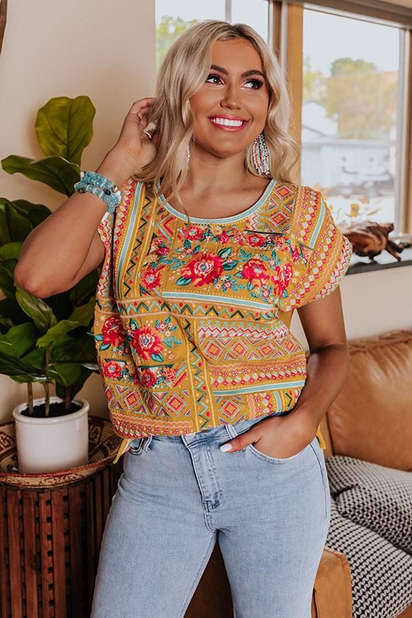 Add a luxurious finish to your look with this eye-catching mustard hued top featuring lightweight material adorned with intricate and colorful embroidered detailing, a rounded neckline, cap sleeves, a solid back, and a relaxed silhouette that falls into a straight hemline! Yellow Bohemian Short Sleeve Blouse, Bohemian Yellow Short Sleeve Blouse, Yellow Embroidered Short Sleeve Top For Spring, Orange Bohemian Top With Floral Embroidery, Yellow Crew Neck Top With Floral Embroidery, Yellow Bohemian T-shirt For Summer, Bohemian Yellow T-shirt For Summer, Casual Yellow Embroidered Short Sleeve Top, Orange Floral Embroidered Short Sleeve Tops