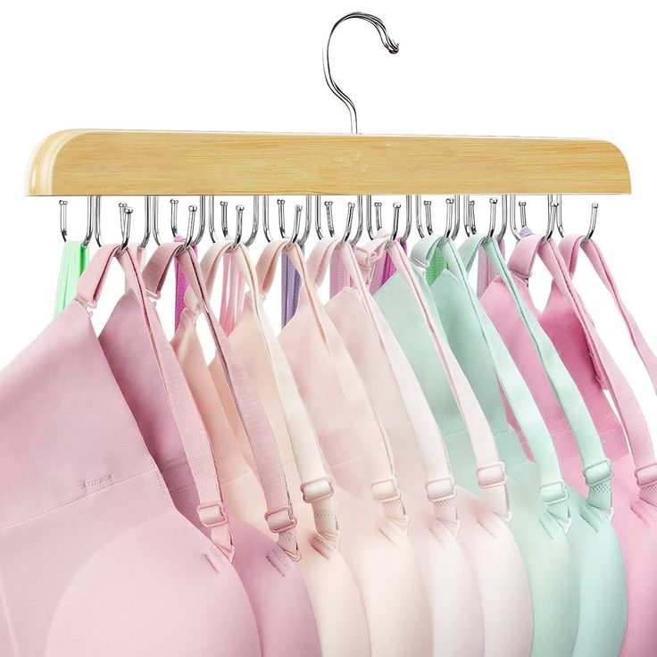 several bras hanging on a wooden hanger in different colors and sizes, including pink