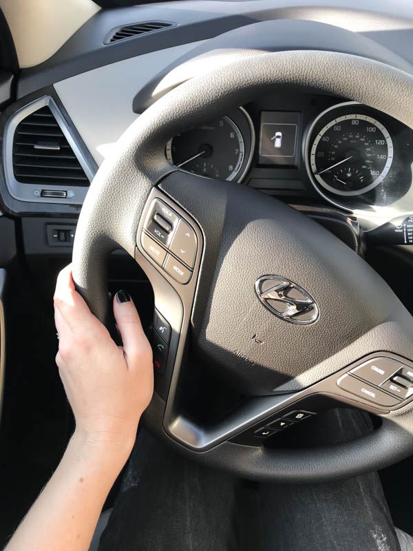 a person is holding the steering wheel and pressing buttons on their car's dashboard