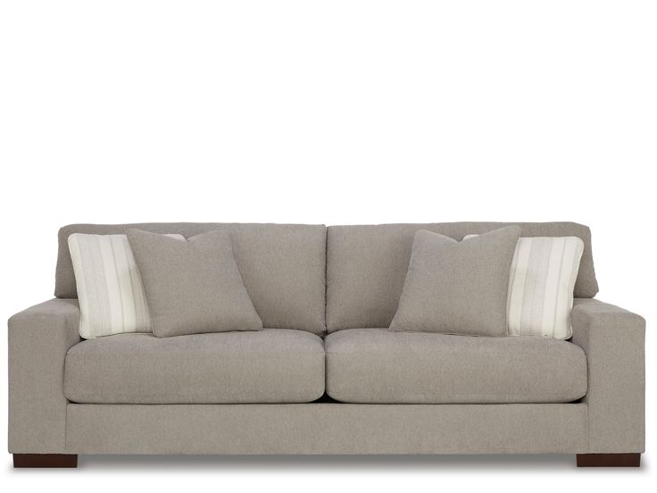 a gray couch with two pillows on it's back and one pillow in the middle