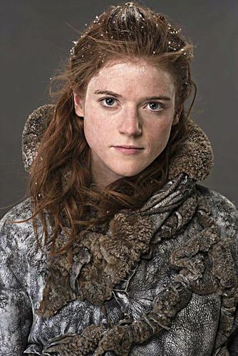 a woman with long red hair wearing a fur coat and scarf, looking at the camera