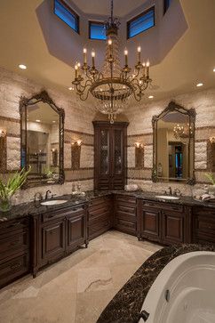 a fancy bathroom with chandelier and marble counter tops, two sinks, large bathtub