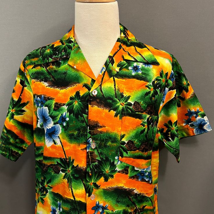 You are viewing a very cool Vintage Men's Cotton Blend Hawaiian or Aloha Shirt c1970s. This great looking shirt is made of a medium weight cotton blend cloth with a printed floral and palm tree pattern in shades of orange, green, gold, yellow and brown. Details include splayed camp collar, 4 button placket (with clear plastic buttons), 10" short sleeves, left patched chest pocket and straight hem. Dates from likely the late 1970s. Retains maker's label at neckline (Hukilau Fashions, Honolulu). F Cotton Hawaiian Shirt With Vintage Print And Camp Collar, Multicolor Cotton Hawaiian Shirt With Hibiscus Print, Hawaiian Shirt With Vintage Print In Cotton, Hawaiian Cotton Shirt With Vintage Print, Cotton Hawaiian Shirt With Retro Print And Camp Collar, Green Cotton Hawaiian Shirt With Camp Collar, Retro Hawaiian Shirt With Camp Collar, Cotton Hawaiian Shirt With Vintage Print, Vintage Cotton Hawaiian Shirt For Vacation